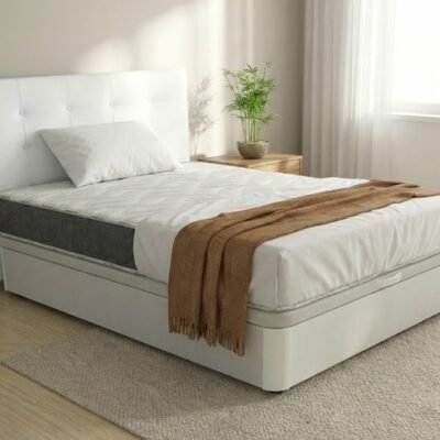 Vista lateral de perfil del Pack de cama completa Nature. Muestra la altura y robustez del canapé abatible de madera blanca y el colchón viscoelástico Eco Bambú con su platabanda gris visible, vestido con almohada blanca y manta marrón en un dormitorio luminoso.