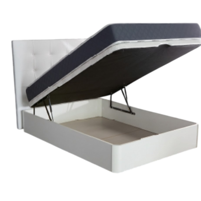 Cama canapé abatible blanca tapizada con cabecero capitoné, colchón gris oscuro elevado por pistones hidráulicos, revelando amplio espacio de almacenaje interior. El canapé descansa sobre un suelo de madera claro con una alfombra beige texturizada, todo sobre un fondo transparente para fácil integración.